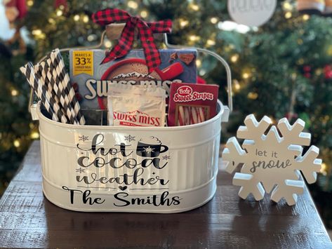 "If you are looking for a great gift for someone who loves hot chocolate in the winter than this white metal caddy is perfect for you! This galvanized caddy has 4 sections- 3 smaller ones in front and 1 larger one in back.  It holds your hot cocoa packets, marshmallows, straws, and peppermint sticks.  The caddy is oval in shape and has a wooden movable handle. The caddy comes with \"Hot Cocoa Weather\" and a family name on the front. This caddy is 10.5\" (L) x 7\" (W) x 5\" (H) without handle & 10\"(H) with handle This listing is for the caddy only.  The hot cocoa ingredients are not included." Gifts With Hot Chocolate Packets, Hot Cocoa Caddy, Hot Chocolate Bar Gift Basket, Hot Chocolate Basket Ideas, Christmas Gift Basket Ideas For Families, Hot Chocolate Gift Basket Ideas, Hot Cocoa Gift Basket Ideas, Hot Chocolate Basket, Hot Cocoa Basket