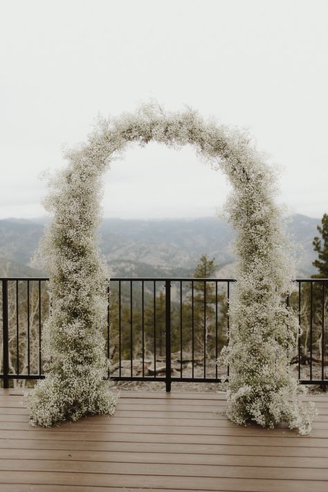 A oval wedding arch completely covered with babies breath flowers sits on a wooden deck with the mountains in the background. Babies Breath Arch, Wedding Aisle Decorations Outdoor, White Wedding Arch, Floral Arch Wedding, Provence Wedding, Dream Wedding Decorations, Cottage Wedding, Green Wedding Colors, Wedding Arch Flowers