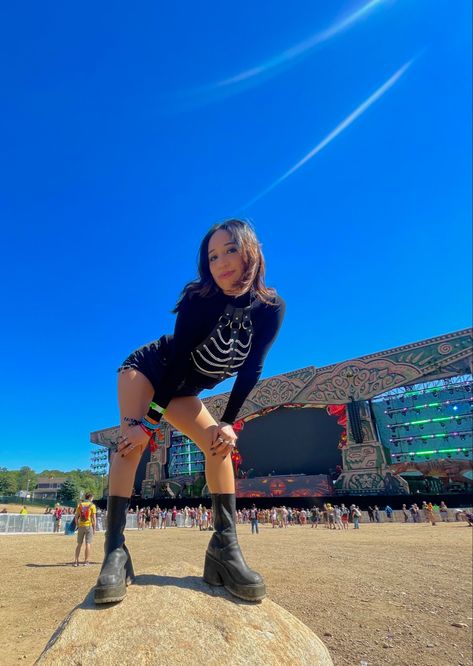 posing in front of the main stage at a music festival wearing black top with leather chain harness and boots Lost Lands Festival Outfit, Elements Outfit, Lost Lands Outfit, Goth Raver Outfit, Rave Totems, Fitted Rave T-shirt For Streetwear, Black Rave T-shirt For Summer, Leather Harness Outfit, Lost Lands Festival