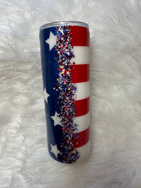 This tumbler is blue with white stars on one side and red and white stripes on the other. Down both sides where they meet is covered with red, white and blue glitter 4th Of July Tumbler Ideas, Patriotic Tumblers, Military Diy, American Flag Tumbler, Tumblr Cup, Tumbler Cups Personalized, Tumbler Making, Flag Crafts, Epoxy Crafts