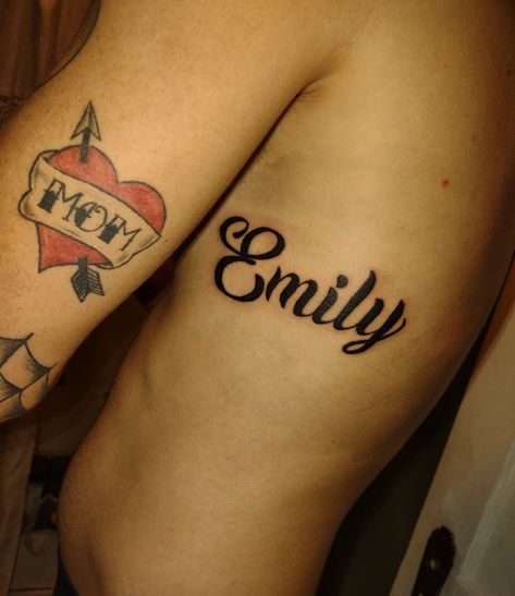 The name Emily tattooed on the ribcage 
Black cursive ink
Unique font Emily Name Tattoo, Emily Tattoo, Emily Name, Tattoo Name, Name Tattoo, Name Tattoos, Rib Cage, A Name, Tattoo On