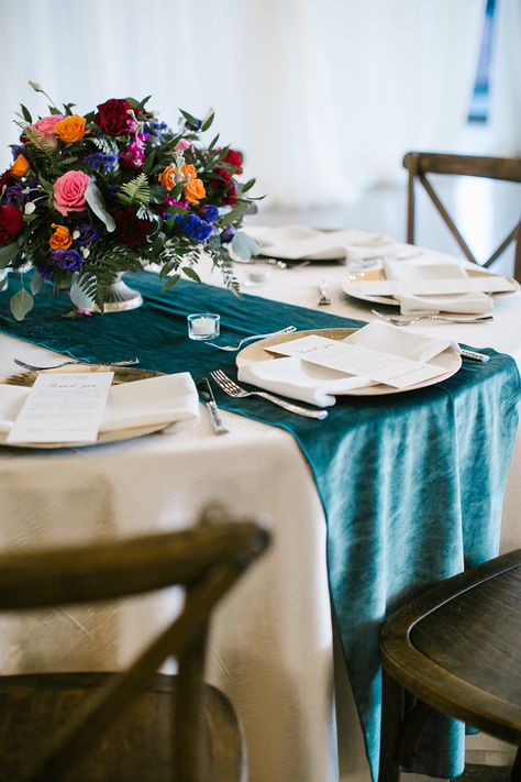 A beautiful upgraded cream linen paired with a dark teal velvet runner. Champagne chargers. Antique brass vases are holding the beautiful jewel-toned flowers and greenery. Linens are from White Table and Florals are Lisa Foster. Dark Teal Table Runner Wedding, Teal Table Setting Wedding, Dark Teal Wedding Table Setting, Dark Teal Table Runner, Teal Table Runner Wedding, Jewel Tone Round Table Wedding, Jewel Tone Table Decor, Dark Teal Table Setting, Jewel Tone Wedding Table Settings