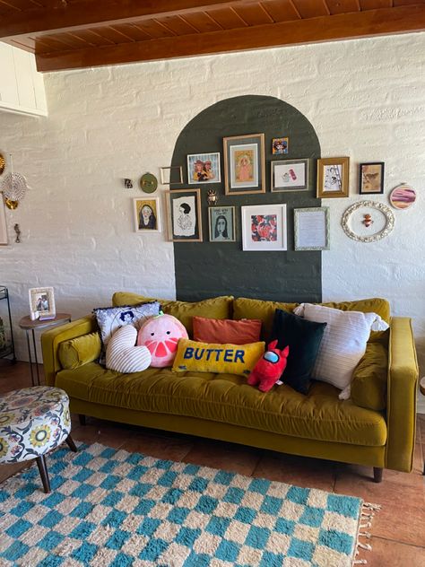 a yellow couch in front of a green arch and blue checkerboard rug. tons of pillows on the couch and a gallery wall on the arch design! Chartreuse Couch Living Room Ideas, Above Couch Wall Decor Eclectic, Living Room Art Wall Above Couch, Yellow Green Sofa, Bright Green Couch Living Room, Green Couch Yellow Walls, Behind Couch Wall Art, Yellow Couch Styling, Arch Behind Couch