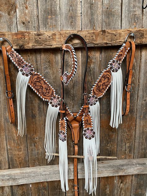 Browband, one ear, wither strap and breastcollar is floral tooled whipstitch style. They are decorated with copper AB crystal conchos/buckles and white fringe. Full Horse size Measurements Headstall measurements : bit to bit - 36" shortest setting : 44" longest settingBrowband measures 15" acrossBreastcollar measurements - From Center Ring to D Ring -16"Breastcollar including toggles : shortest settings - 26" : Longest settings -29" Lifetime guarantee on all crystals.Buy Together or Separate BRO Barrel Tack Sets, Wither Straps For Horses, Western Tack Sets Barrel Racing, Tack Sets Western, Horse Tack Sets, Western Riding Tack, Western Tack Sets, Barrel Racing Tack Sets, Barrel Racing Tack Rodeo