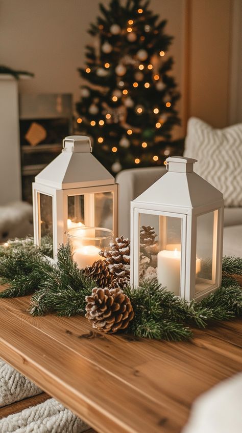 Cozy living room coffee table adorned with white lanterns, pine cones, greenery, and soft winter lighting decorations. Winter Lantern Decor, Cozy Coffee Table, Festive Living Room, Living Room For Christmas, Winter Lantern, Living Room Christmas Decor Ideas, Room Christmas Decor Ideas, Living Room Christmas Decor, Christmas Living Room Decor