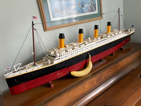 The LEGO Titanic, at 9090 pieces, is simply massive! It’s some 53” long, and here it is pictured atop a piano with a (fairly large) banana for scale. Lego Titanic Display, Lego Eiffel Tower, Lego Room Decor, Lego Titanic, Lego Display, Crochet Baby Shoes Pattern, House Essentials, Baby Shoes Pattern, Lego Creative