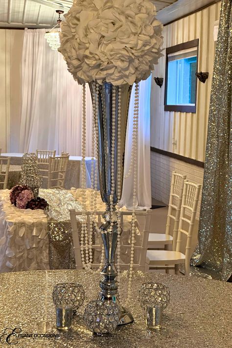 Silver sequin table cloth with stemless crystal beaded goblet votives and a table number surrounding a white flower ball on top of a tall silver trumpet vase draped with pearls Diamonds And Pearls Birthday Party Theme, Diamond And Pearls Party Theme, Diamonds And Pearls Theme Birthday, Pearl Anniversary Party, Diamonds And Pearls Theme, Pearl Centerpieces, Pearl Wedding Centerpieces, 60th Wedding Anniversary Decorations, Diamond Wedding Theme