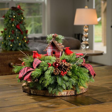 Inspired by the delight of glimpsing the striking red feathers of a cardinal flutter through the forest, our Cardinal Cottage centerpiece is a truly cherished addition to the home of any bird or nature lover! This Christmas centerpiece features two adorable bright red cardinal birds nestled in close to a rustic birdhouse and surrounded by a forest of fresh noble fir, white pine, and incense cedar. Their bountiful home is teeming with cheery red faux berries, pinecones, shiny red balls, and is ac