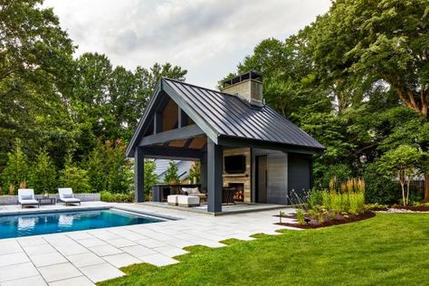 The stone patio of this modern backyard has uneven edges to create visual interest in this modern space. The sleek metal roof is a dark contrast to the custom chimney and fireplace. Pool Pavilion Ideas, Pool House Cabana, Lap Pool Designs, Pool House Design, Backyard Pool Design, Pool Pavilion, Poolside Dining, Pool Remodel, Pool Pool