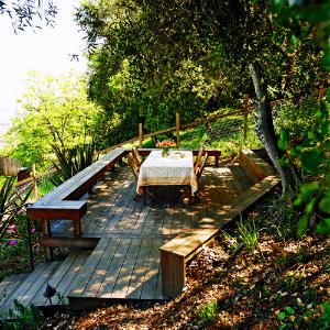 Taming a slope    A deck at the top of this sloping backyard transformed the space into an inviting destination for taking in the view.    The rear edge of the 15- by 24-foot deck notches into the hill. A low retaining wall holds the uphill section in place and doubles as another bench seat. Hillside Deck, Steep Backyard, Sloped Yard, Sloped Backyard, Hillside Landscaping, Sloped Garden, Fire Pit Area, Decks Backyard, Backyard Deck