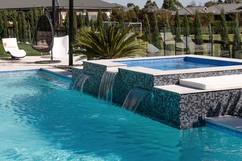 Add a feature spa to your Crystal Pool! The dark tiled raised spa with spillover water feature is the showstopper for this Luddenham family's backyard. Contrasting tiles like these are becoming a popular trend. #pooltiles #contrastingtiles #raisedspa #spilloverspa #featurespa Raised Spa With Spillover, Spa Waterfall, Raised Pools, Swimming Pool Design Ideas, Concrete Swimming Pool, Pool Design Ideas, Family Backyard, Dark Tile, Pool Remodel