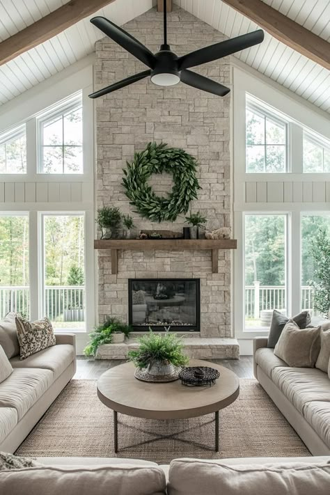 Modern farmhouse living room with stone fireplace a big green wreath above the mantel near vaulted ceiling ceiling in reclaimed wood slats large. Check out all of these dream farmhouses that will have you drooling with rural living fantasies and mooing with joy! Fireplace To Ceiling Stone, Styles Of Fireplaces, Farmhouse Living Room Stone Fireplace, Wooden Mantle On Stone Fireplace, White House With Greenery, Fireplace For Vaulted Ceiling, Stone Fireplace And Hearth, Fireplace In High Ceiling Room, Fireplaces With Cathedral Ceilings