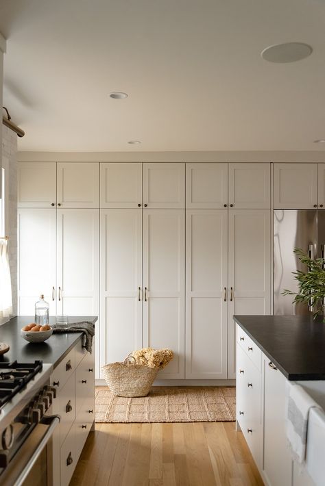 Modern farmhouse kitchen featuring old world charm and European influences. This kitchen has ceiling to counter handmade ceramic backsplash tiles paired with a patina soapstone counters. Warm tones layered in with unlacquered brass accents in the light fixtures and cabinetry hardware. Painted greige cabinetry seamlessly integrate with the contrast trim throughout the home. Featuring floor to ceiling built-ins to provide extra functionality for the growing family. Full Height Cabinets Kitchen, Kitchen Wall Built Ins, Floor To Ceiling Wall Cabinets Kitchen, White Floor To Ceiling Cabinets, Kitchen Wall Of Cabinets Built Ins, Small Kitchen Floor To Ceiling Cabinets, Floor To Ceiling Kitchen Storage, Small Kitchen Tall Ceilings, Small Kitchen Built In