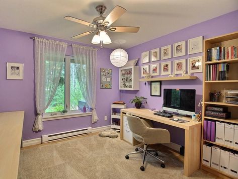 Redecorated in 2016, my office allows me space for both my day job and my 'true calling' (the works of Zoe Mullins - some of the covers which you can see hanging above my desk.). The laminate floors are original but durable for the dogs. The area rug (there have been many over the years) keep the feet warm beneath my desk.   The purple may be more 'girlie' than you expect from me, but to me it is both calming and  inspiring. (It is a big room - and used to fit a king size bed and dresser!) Purple Office Decor Ideas, Purple Wall Office, Rooms With Purple Walls, Lilac Home Office, Home Office Purple, Purple Home Office Ideas, Purple Office Aesthetic, Light Purple Office, Purple Home Offices