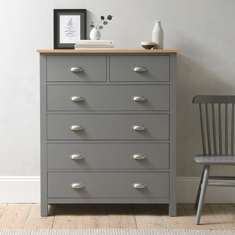 If it’s time to ring the changes in your bedroom, it’s worth considering the effortless elegance of our Simply Cotswold range. Fusing modern design and country style, the 6 Drawer Tall Chest will be a striking addition to your bedroom scheme. The grey paint finish contrasts wonderfully with the solid oak top and brushed steel cup handles for a unique look that will suit many decors. Six spacious drawers provide plenty of storage, and its tall, slim footprint maximises space.This range was former Drawer Decor, Stone Farmhouse, British Furniture, Storm Grey, Grey Paint, 2023 Vision, Tall Chest, Wood Chest, Cup Handles