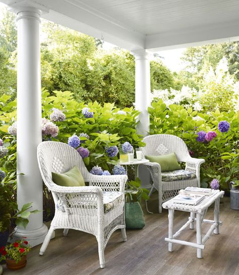 Looks so inviting!  (From Country Living Magazine)white wicker chairs, white columns surrounded by colorful hydragenas Beach House Porch, White Wicker Furniture, Oversized Chair, Wicker Decor, Casa Exterior, House With Porch, White Wicker, Wicker Chairs, Front Porches