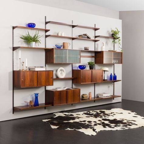 An elegant and functional shelving system in rosewood designed by Kai Kristiansen in the 60s and manufactured by FM Mobler is an impressive four-bay entirely modular set. The preserved manufacturer's label validates its origin.  Five cabinets and thirteen shelves provide enough space for storage, books, and decorations. The wall unit features brilliant carpentry and a rich wood grain of rosewood veneer with solid wood details. Each section is 86cm wide, and one can arrange all the parts as neede Cabinets With Sliding Doors, Mid Century Shelving, Cabinet With Sliding Doors, Storage Books, Built In Wall Units, Mid Century Interior Design, Dnevna Soba, Cabinets With Glass Doors, Mid Century Interior