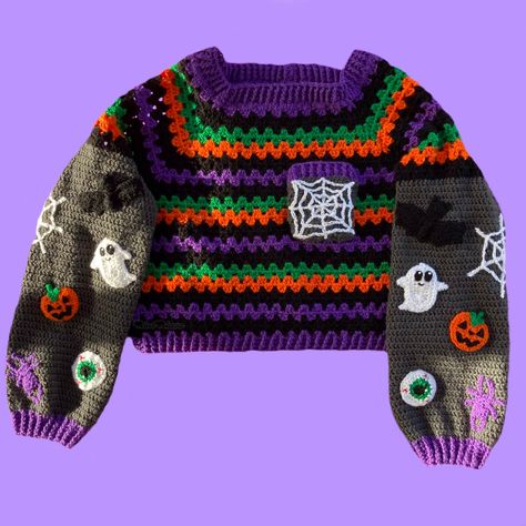 Please note that we have currently reached our capacity for jumper orders so there is a wait of 1 month for these to be made and dispatched, please keep this in mind if you are planning to order other items at the same time as they will all be dispatched together. Whether Halloween is a day, a whole month or every day for you, our Cropped Spooky Season Jumper will keep you creepy, cute and cosy. Crocheted from premium quality, hardwearing and vegan friendly acrylic yarn in classic Halloween colours. The sweater features a granny stitch Black, Violet, Pumpkin Orange and Emerald Green striped main with a Granite Grey square chest pocket that features a white spider web. The jumper features long sleeves that are Granite Grey with Ghost, Spider Web, Pumpkin, Spider, Bat & Eyeball appliqués. Th Horror Movie Granny Square, Crochet Cardigan Halloween, Granny Square Crochet Pattern Halloween, Halloween Sweater Crochet Pattern, Crochet Halloween Clothes, Halloween Crochet Sweater, Granny Square Halloween, Crochet Halloween Sweater, Crochet Granny Square Jumper