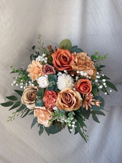 "More beautiful wedding flowers https://bridalstoryus.etsy.com  Orange terracotta rust bridal wedding bouquet is created with high quality silk flowers. These handmade artificial wedding bouquets make beautiful additions to wedding and event floral arrangements. Flowers: peonies, roses, wild flowers, eucalyptus and fillers.  Colors: orange, terracotta, beige, rust, white, pale champagne, green. Handle: wrapped in ivory satin ribbon. Size: bridal bouquet is approximately 14\" wide, bridesmaids bouquet is 8\". SUGGESTION: steaming the bouquets upon receiving them and you will see how easily they will take the original shape and wrinkles will be removed too. Purchase options: * Bridal bouquet 14\" * Bridesmaids bouquet 8\" * Boutonniere * Corsage" Fall Rose Bouquet Wedding, Bouquets For Fall Wedding, Eucalyptus And Rust Bouquet, Bouquet Wrap Ideas Wedding, Rustic Orange Wedding Flowers, Wedding Bouquets Bride Orange, Cabernet And Rust Wedding, Sage Green And Terracotta Wedding Bouquet, Blush And Terracotta Bouquet