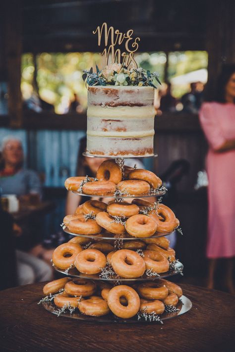 Cake With Donuts Wedding, Cake And Doughnuts Wedding, Doughnut Wedding Cakes, Rustic Donut Cake Wedding Ideas, Donut Cakes Wedding, Krispy Kreme Wedding Cake Donut Tower, Wedding Cake With Donuts Around, Donuts Wedding Cake, Wedding Doughnut Cake