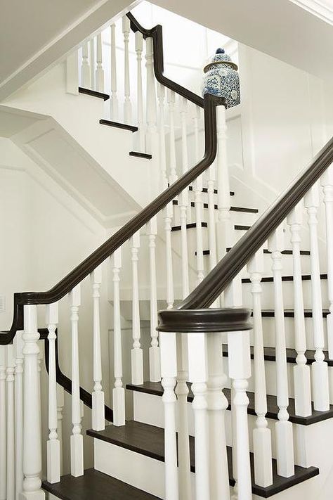 A white staircase with white spindles is contrasted with dark brown treads and a dark brown handrail. Brown Staircase, Stairs Makeover Design, Staircase Spindles, Cottage Stairs, Black And White Stairs, Foyer With Stairs, Stairs And Doors, White Staircase, White Stairs