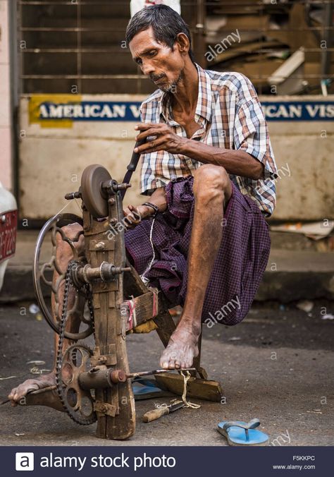 Download this stock image: Yangon, Yangon Division, Myanmar. 6th Nov, 2015. A knife grinder with his pedal powered grinding stone works on a Yangon street. He walks through the city announcing his services and sharpens people's knives for the equivalent of few cents each. Some economists think Myanmar's informal economy is larger than the formal economy. Many people are self employed in cash only businesses like street food, occasional labor and day work, selling betel, or working out of portabl Knife Grinder, Self Employed, Pedal Power, Yangon, Metal Tools, Day Work, Myanmar, Wood And Metal, Street Food