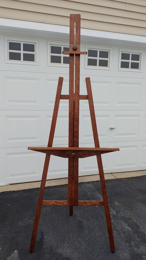 A beautiful floor standing display easel in solid cherry, handcrafted by Mark for displays up to 53" high. This easel can add a touch of class to events in galleries, churches, convention centers,  and more. Decorative solid brass hinges are now standard. The hinged kickstand locks while in use and when folded against the mast for storage or transport. The kickstand is held open by a solid wood strut. I carefully selected cherry hardwood boards which I dimensioned, planed, and sanded. Finally, I finished the wood with a black cherry stain and two coats of satin polyurethane. This easel is suitable for indoor or outdoor use and stands firm and quiet on rubber feet. I suggest a 20 lb. maximum load. The top clamp features a 5o bevel that will secure even very thin items like rigid poster boar Cherry Floors, Standing Display, Cherry Stain, Cherry Hardwood, Display Easel, Brass Hinges, Black Cherry, Touch Of Class, The Struts