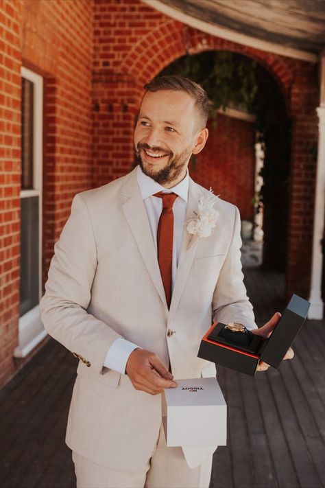 A groom smiling to someone off camera holding a gifted watch. Cocktail Attire Men Wedding, Garden Party Outfits, Cocktail Attire Men, Groom And Groomsmen Suits, Cream Suit, Modern Groom, Orange Suit, Burnt Orange Weddings, Beige Suits