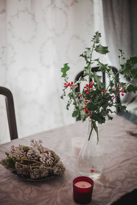 Vase with holly and Christmas decorations on a table Centerpieces Diy, Christmas Centerpieces Diy, Tree Trimming, Old Fashioned Christmas, Magical Christmas, Christmas Holly, Christmas Centerpieces, Christmas Table, Christmas Traditions