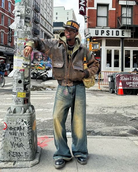 Vintage Vibe 🍩 How about his color? 📸 @knawtkai 🇺🇸 🧢Cap : free the youth 👔Hoodie : trendtvision 👞Shoes : dr.martens 👜Bag : louis vuitton Embodying the vintage vibes of American streets, this man’s outfit exudes timeless coolness. The combination of the vintage brown leather jacket and washed baggy jeans sets the tone, while the ‘Trendtvision’ khaki zipped hoodie and black printed shirt add depth to the ensemble. Elevating the look further, the ‘Dr. Martens’ black boots and ‘Free the Y... Brown Docs Outfit Men, Fits With Docs, Brown Jacket Men Outfit, Vintage Jacket Outfit Men, Men’s Leather Jackets Outfit, Vintage Baggy Outfit, Cool Leather Jackets, Baggy Jeans With Boots, Leather Outfits Men