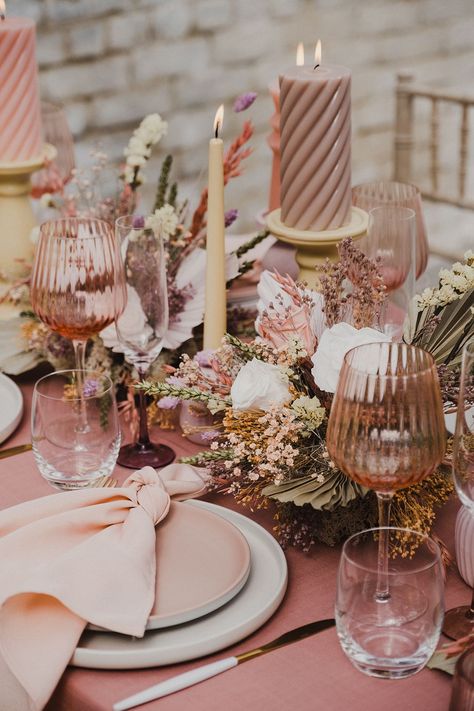 Wedding table decor and preserved pastel flowers centrepiece with palm leaves, coloured goblets, church candles and more Coloured Glassware Wedding, Pink Glassware Table Setting, Pastel Dried Flowers, Pastel Flowers Wedding, Pink Table Decorations, Coloured Glassware, Bud Vases Arrangements, Dried Wedding Flowers, Dried Palm Leaves