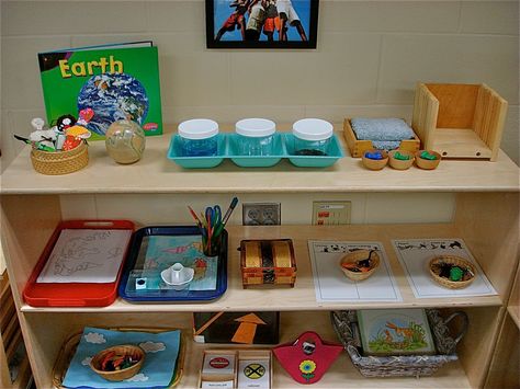 This a "culture shelf" in a Montessori classroom. Montessori Layout, Montessori Extensions, Montessori Classroom Layout, Montessori Culture, Montessori Shelves, Montessori Board, Montessori Shelf, Montessori Science, Montessori Teacher