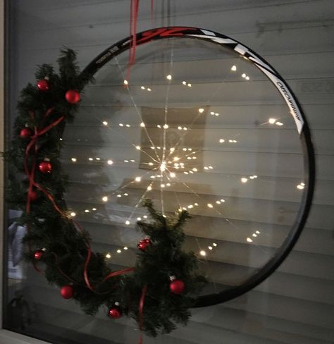 My husband and I are avid cyclist. All six of our bikes, which we ride frequently, live inside the house and are mounted on the walls as our "Ridable Art". We have many used bicycle parts and I decided to make one of our old wheel rims into a Christmas wreath.   Repurposing an old Bicycle wheel into a Christmas Wreath.   I started with a string of battery powered Fairy Lights.    And an old bicycle wheel rim. None of our old rims have spokes in them so I went for the illusion of spokes… Bicycle Wheel Decor, Bicycle Crafts, Battery Powered Fairy Lights, Bicycle Rims, Bicycle Decor, Old Bicycle, Wheel Decor, Deco Mesh Christmas Wreaths, Wheel Art