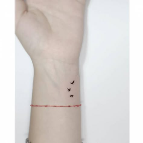 Minimalistic style flying birds tattooed on the wrist. Let It Be Tattoo With Birds, Three Small Birds Tattoo Simple, Small Bird Wrist Tattoos For Women, Birds Flying Tattoo Arm, Three Flying Birds Tattoo, Minimalist Tattoo Freedom, Birds On Wrist Tattoo, Tiny Sparrow Tattoos For Women, Minimalist Tattoos For Women Wrist