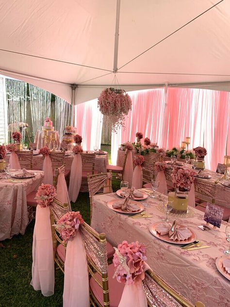 Elevate your outdoor party design with pink-themed decorations. Cover the tables with pink tablecloths and place rose gold metal and acrylic chargers for a perfect place setting. Bedeck the party chairs with gold sequin spandex sashes and drape pink chiffon sashes from the back along with a bunch of blush pink hydrangea bushes for flawless grandeur. Furthermore, dangle pink chiffon and silver tinsel curtains and hang rose gold vine garlands from the ceiling for a splendid look. Quince Decorations Pink, Pink Tablecloths, Pink Chair Covers, 21st Birthday Party Decor, Rose Gold Chair, Pink Table Decorations, Birthday Setup, Event Decor Ideas, Pink Gold Party