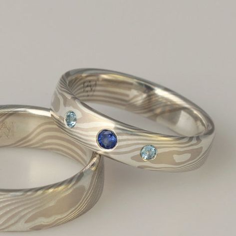 This classic woodgrain pattern mokume gane ring is 5mm wide, made with 14k palladium white gold and sterling silver, and set with three stones; a central ceylon sapphire and flanking swiss blue topaz. Prices quoted are good for ONE RING without stones, sizes up to 9.75 - please contact me for a quote for larger sizes.Add-on:Stones and cost of setting not included, please contact me for a custom quote - I can set any stone you provide, 3-6mm in width, or I can provide a stone for you. I recommend Gold And Silver Ring, Mokume Gane Ring, Woodgrain Pattern, Custom Wedding Rings, Mokume Gane, Ceylon Sapphire, Gold And Silver Rings, Swiss Blue Topaz, One Ring