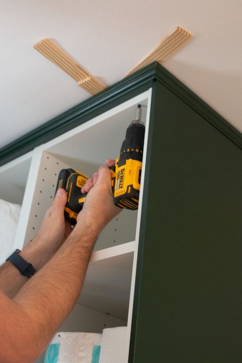 Adding crown molding to the ceiling. Come learn our tips for installing IKEA kitchen cabinets and making them look high-end and built-in. We used these dark green cabinets in our laundry room and they turned out absolutely gorgeous! #IKEA #ikeakitchen #DIYkitchencabinets Crown Molding On Ikea Kitchen Cabinets, Ikea Kitchen Cabinet Hacks Built Ins, Ikea Crown Molding, Wall Kitchen Cabinets Ideas, Upper Cabinet Molding, Installing Ikea Kitchen Cabinets, Ikea Kitchen Crown Molding, Ikea Sektion Axstad Kitchen, Ikea Hacks Kitchen Cabinets