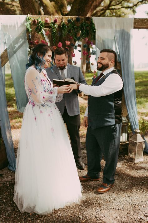 A magical DnD-themed wedding! 🌸🎲 From the bride putting on the groom's ring to their first kiss and celebrating up the aisle, these moments are pure enchantment. The floral dress, the wooden arch with blue ombré draping, and the whimsical flower backdrop add a touch of fantasy to this special day. Warhammer Wedding, Dnd Wedding Ideas, D&d Wedding, Dnd Wedding, Dragon Wedding, Nerdy Wedding, Whimsical Flower, Groom Ring, Wooden Arch