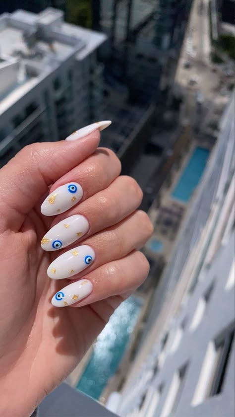 Greece evil eye gold flakes mani pedi nail manicure design trendy summer nails white sleek classic classy hot beach spring trending Europe vacation vacay Miami Greek inspo inspiration Blue Eye Nail Art, Trendy Nails Evil Eye, Nail Design With Evil Eye, Almond Nails French Tip Evil Eye, Eye Nail Art Evil, Evil Eye Nails With Gold, Evil Eye Nails Almond Shape, White Nails Evil Eye Design, Devils Eye Nails