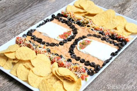 Instead of putting the refried beans on the bottom, they'll take center stage. Spread the guacamole on the bottom of the tray, covering with a layer of refried beans. Use the sour cream to create the key. Consider piping it on using a pastry bag. Sliced black olives are ideally suited for the three-point line. Your court is easily rounded out with salsa, cheese and sliced green onions on the sidelines. To go along with March Madness date March Madness Food, Basketball Food, Basketball Snacks, Basketball Treats, March Madness Parties, Snack Stadium, Basketball Theme Party, Snack Trays, Basketball Birthday Parties