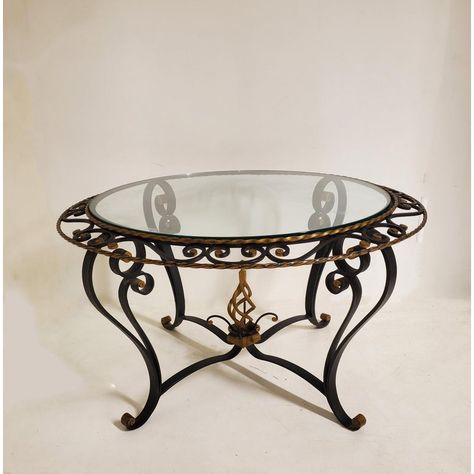 A French Art Deco circular coffee table expertly crafted in hand forged iron and finished in tones of gold and black, attributed to Poillerat The combination of the two colors creates a beautiful contrast to enhance any living space. The table features a delicate scroll border and a double rope twist rim surround that adds an intricate touch to the design. At the center of the "X" form stretcher of the table base, is an ornamental flame which creates a stunning focal point. The flame design is f Wrought Iron Tables, Iron And Glass Coffee Table, Wrought Iron Side Table, Wrought Iron Cocktail Table, Wrought Iron Coffee Table With Glass Top, Steel Furniture Design, Circular Coffee Table, Fine Antique Furniture, Metal Bending Tools