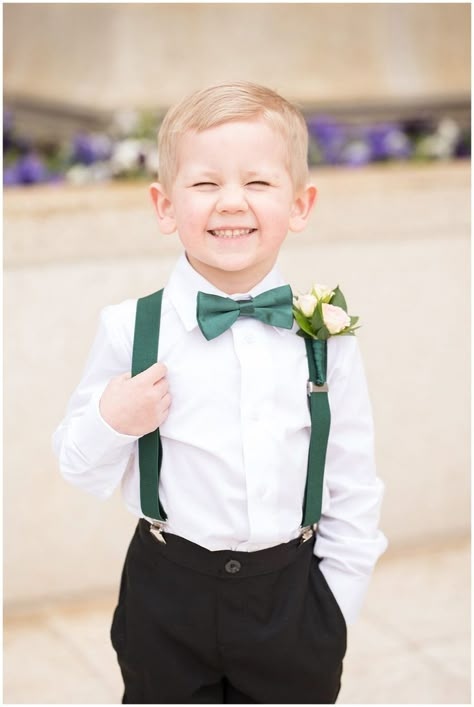 Ring bearer cheesy smile at the camera with emerald green suspenders and bowtie | Ogden Temple Winter Wedding | Emerald Green and Pink Wedding | Jessie and Dallin Photography Ring Bearer Emerald Green, Black Tux Emerald Green Tie, Emerald Ring Bearer, Emerald Green Black White Silver Wedding, Forest Green Ring Bearer Outfit, Emerald Quinceanera Centerpieces, Winter Emerald Green Wedding, Emareld Green Wedding Theme, Ringbearer Cute Ideas