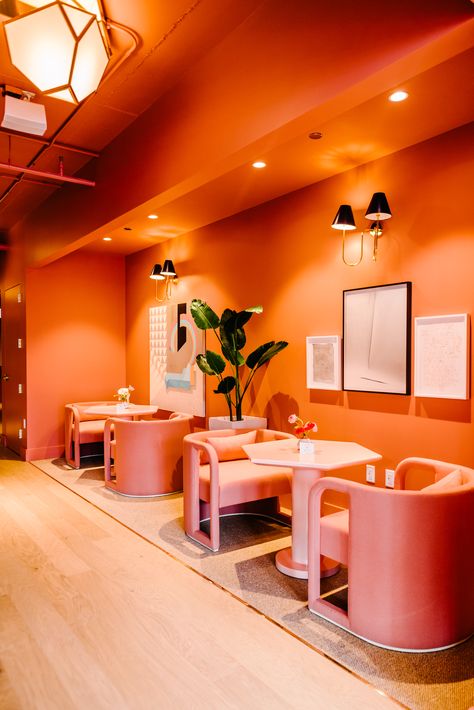 Featured in Domino magazine, Maharam textile Twill Weave by Kvadrat can be seen throughout the Wing's Chicago space. Photography by Jasmine Pulley. Interior design by Laetitia Gorra, The Wing  #Pink #Bright #Coral Orange Interior Design Restaurant, Colorful Commercial Interior Design, Orange Interior Design, Orange Cafe, Lounge Aesthetic, Industrial Decor Living Room, Industrial Bathroom Decor, Restaurant Design Inspiration, Domino Magazine