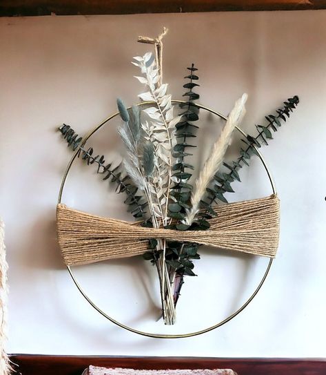 Fleurs séchées oval! Enhance your living space with this stunning Boho Hoop Wreath featuring and a beautiful combination of dried eucalyptus, ruscus leaves, pampas grass and bunny tails. Perfect for adding a touch of nature to any room in your home, this farmhouse boho style hoop is crafted on a gold metal ring with jute cord. Hang it on a wall, display it on a shelf, or use it as a captivating centerpiece to create a focal point in any space. The possibilities are endless! It also makes a thoug Dried Eucalyptus Wall Hanging, Dried Flowers Embroidery Hoop, Boho Christmas Decor Living Room, Gold Hoop Macrame Diy, Metal Ring Crafts Ideas, Wire Hoop Wreath, Boho Fall Crafts, Diy Eucalyptus Wreath, Boho Wreath Ideas