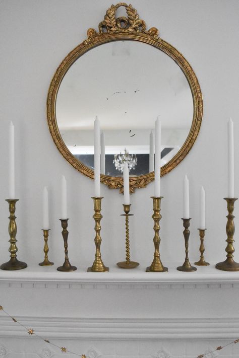 Nine brass candlesticks of various heights with white taper candles Mantle With Black Candlesticks, Antique Brass Home Decor, Tapered Candle Mantle, Candle Mantel Decor, Dining Table Decor Candle Sticks, Candlestick Mantle Decor, How To Style Brass Candlesticks, Brass Candle Holders Decor Ideas, Brass Candlesticks Decor Living Rooms