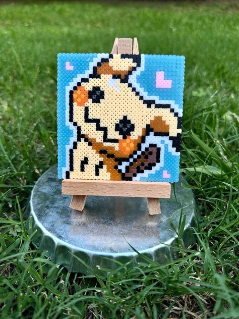 All this little ghosty poke boi wants is to be loved, will you help him get his wish? Each piece is made with love using mini perler beads, and would give a fantastic pop of color to any space in your home. Great as a gift or stocking stuffer for any loved one too! Each piece is individually made by hand so please be aware that there may be some minor variations from listing image. Listing price includes one perler art piece measuring approximately 3.5"x3.5", and one small wooden easel measuring Easy Perler Bead Ideas Simple, Mimikyu Perler Beads, Garfield Perler Beads, Perler Bead Cute, Square Pixel Art, Small Perler Beads, Perler Bead Patterns Pokemon, One Piece Perler Beads, Cute Perler Bead Patterns