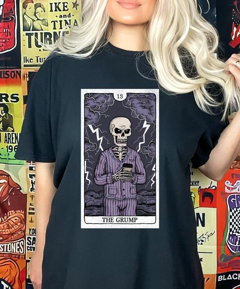 Display your inner goth with this grumpy skeleton tarot card product. Perfect for tarot enthusiasts, witchy souls, and anyone who loves a little dark humor. Ideal for Halloween or just to display your spooky side.  Great for friends who love tarot, witches, or anything spooky. Whether it's for a birthday, holiday, or just because, this product is sure to bring a smile to anyone who loves the occult and things eerie. Comfort Colors introduces the "Comfort Colors 1717" garment-dyed t-shirt; a full Tarot Card Shirt, Skeleton Tshirt, Witchy Aesthetic, Dark Sense Of Humor, Comfort Colors Tshirt, Funny Skeleton, Halloween Tees, Comfort Colors Tee, Retro Halloween