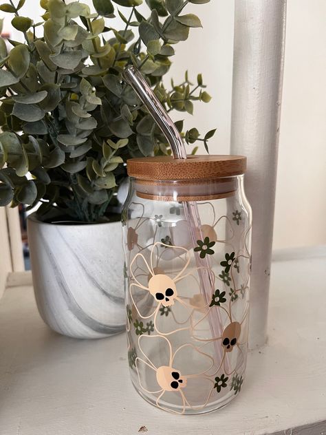 This glass can is toned down with the neutral tones, but if you look real close, you can see the skulls in the daisies. Perfect glass to keep the spooky vibes alive this spring! You can choose to add the bamboo with pink glass straw, just select the option when checking out. Please note that each item is handmade (with love!) and may not look exactly like what is photographed, or might have minor flaws. However, this makes each item unique and special! To extend the life of your glass, follow these care instructions:  **These glasses should be hand washed only ** **Do not put in the dishwasher**  **Do not soak** **OK for warm beverage use, but do not microwave** Minimalist, halloween glass can, spooky libbey glass, libbey glass can, goth glass can, glass tumbler, spooky tumbler, halloween Halloween Cup Ideas, Spooky Spring, Gothic Spring, Spooky Tumbler, Glass Tumbler Design, Easter Cups, Halloween Beer, Nice Tattoos, Minimalist Halloween