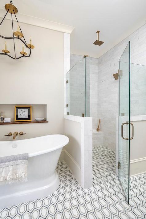 Floor level shower with white, gray and black geometric floor tiles featuring a zero-entry glass-enclosed walk-in shower with a brass kit and staggered marble wall tiles. Zero Entry Shower Ideas, Pike Properties, Bathroom Facelift, Geometric Floor Tiles, Condo Bathroom, Geometric Floor, Cottage Bathroom, Remodel Inspiration, Master Bath Remodel