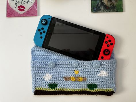 Mario crochet case and sleeve with a Nintendo Switch going into the sleeve. The sleeve is blue with scenes from Mario like the coin boxes, clouds and green pipes. Switch Crochet Case, Nintendo Switch Crochet, Crochet Nintendo Switch Case, Crochet Switch Case, Small Business Clothes, Nintendo Case, Nintendo Crochet, Small Makeup Pouch, Switch Case